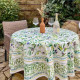 Nappe ronde à motif d’olivier mise en scène sur une table en extérieur dans un décor provençal.